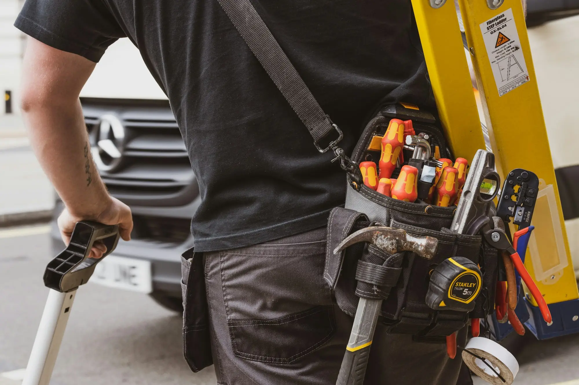 Tradesperson loading tools into the tray of a ute outside a Brisbane job site